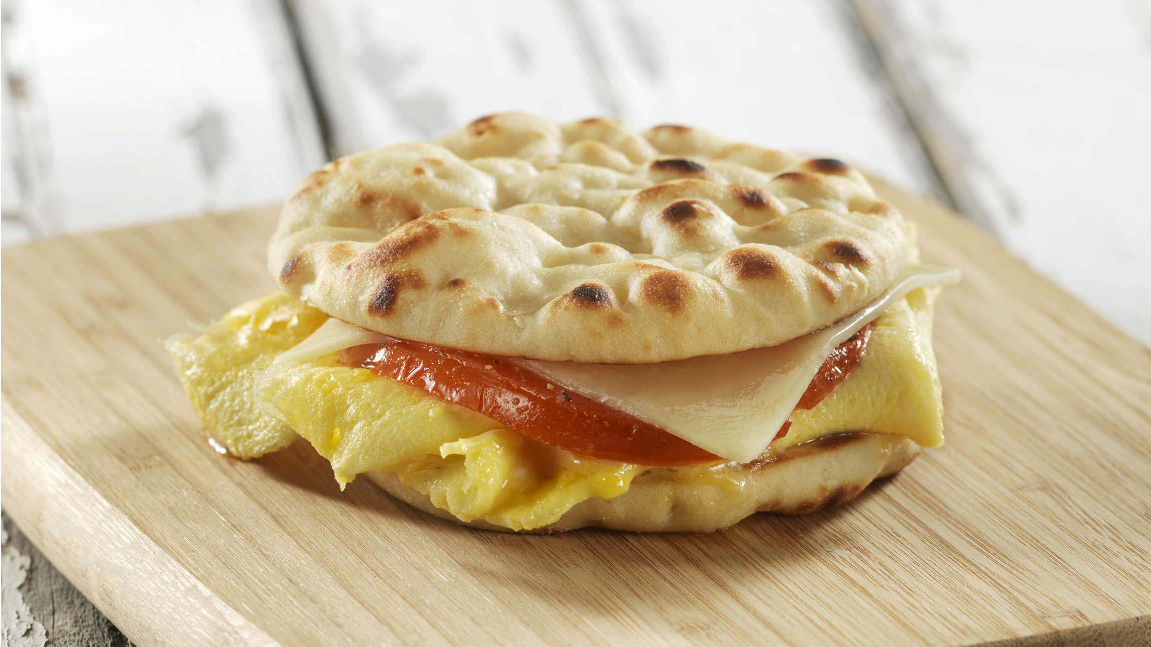 An easy and quick egg, cheese and tomato breakfast sandwich made with Stonefire Original Naan Rounds