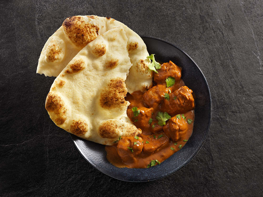 Delicious curry paired with traditional naan bread, illustrating 'What is Naan?' in Indian cuisine.